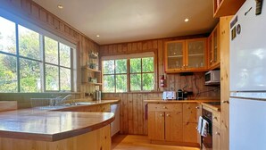 A kitchen with wooden cabinets, a built-in microwave, and a large window.