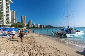 A beach with a sailboat, people on the sand, and tall buildings in the background. - Cozy Studio In Heart Of Waikiki - Free Parking (Honolulu)