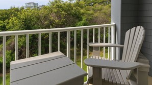 A balcony with a white railing, a gray Adirondack chair, and a small table.