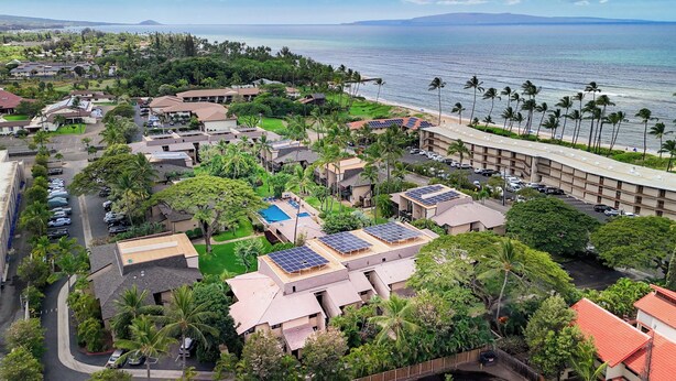 Zona residencial costera con casas, paneles solares y vista al mar.