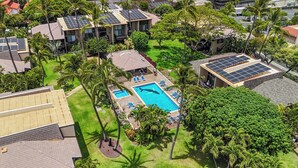 Vista aérea de un complejo turístico con varias edificaciones, una piscina y paneles solares en los tejados.