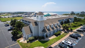 A large hotel with multiple buildings, a parking lot, and a view of the ocean.