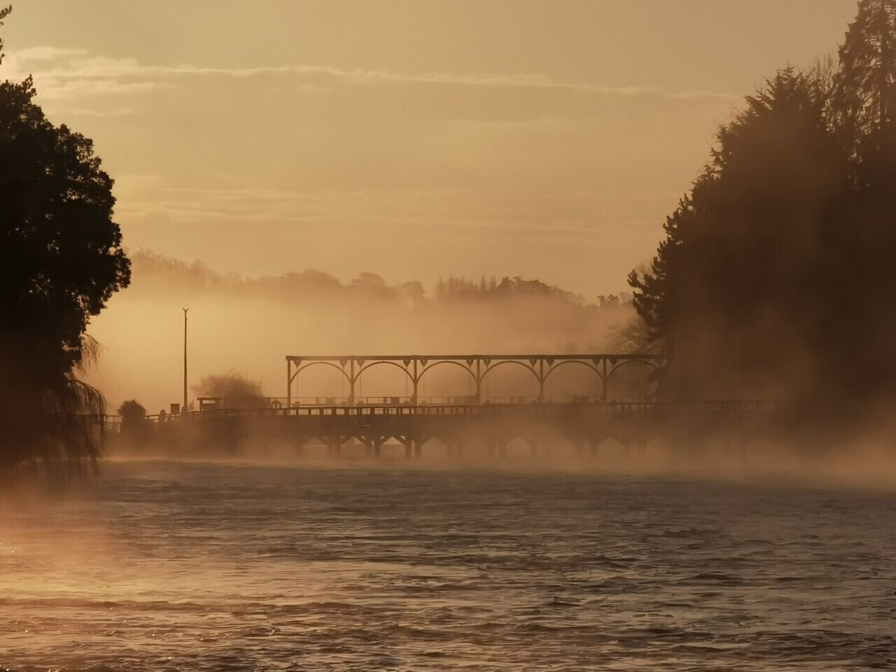 Un ponte che scavalca uno specchio d'acqua avvolto dalla nebbia.