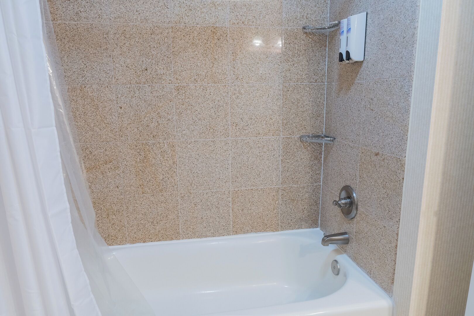 A bathroom with a bathtub, tiled walls, and a showerhead.