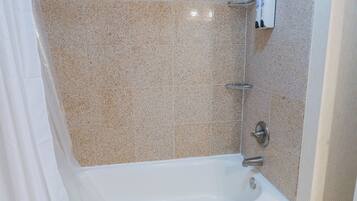 A bathroom with a bathtub, tiled walls, and a showerhead.