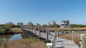 A wooden pier leading to a row of houses by a calm body of water.