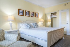 A neatly arranged bedroom with a bed, two bedside tables with lamps, a chair, and a mirror.