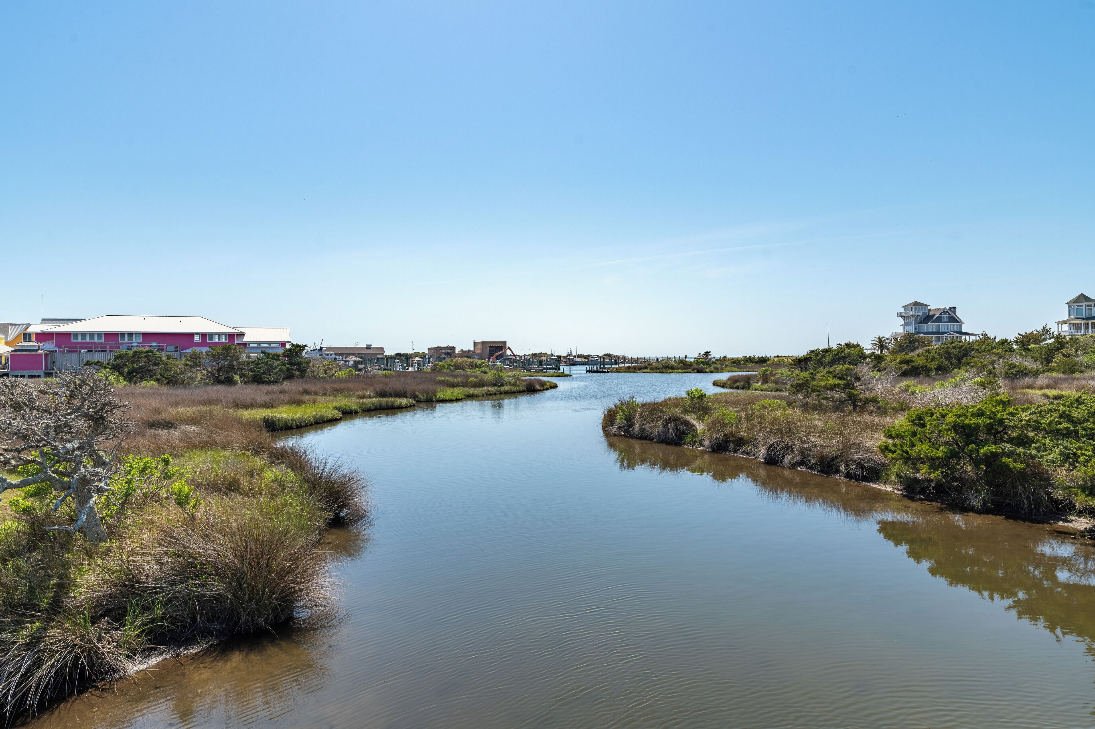 Un río serpentea a través de un paisaje pantanoso con edificios en sus orillas.