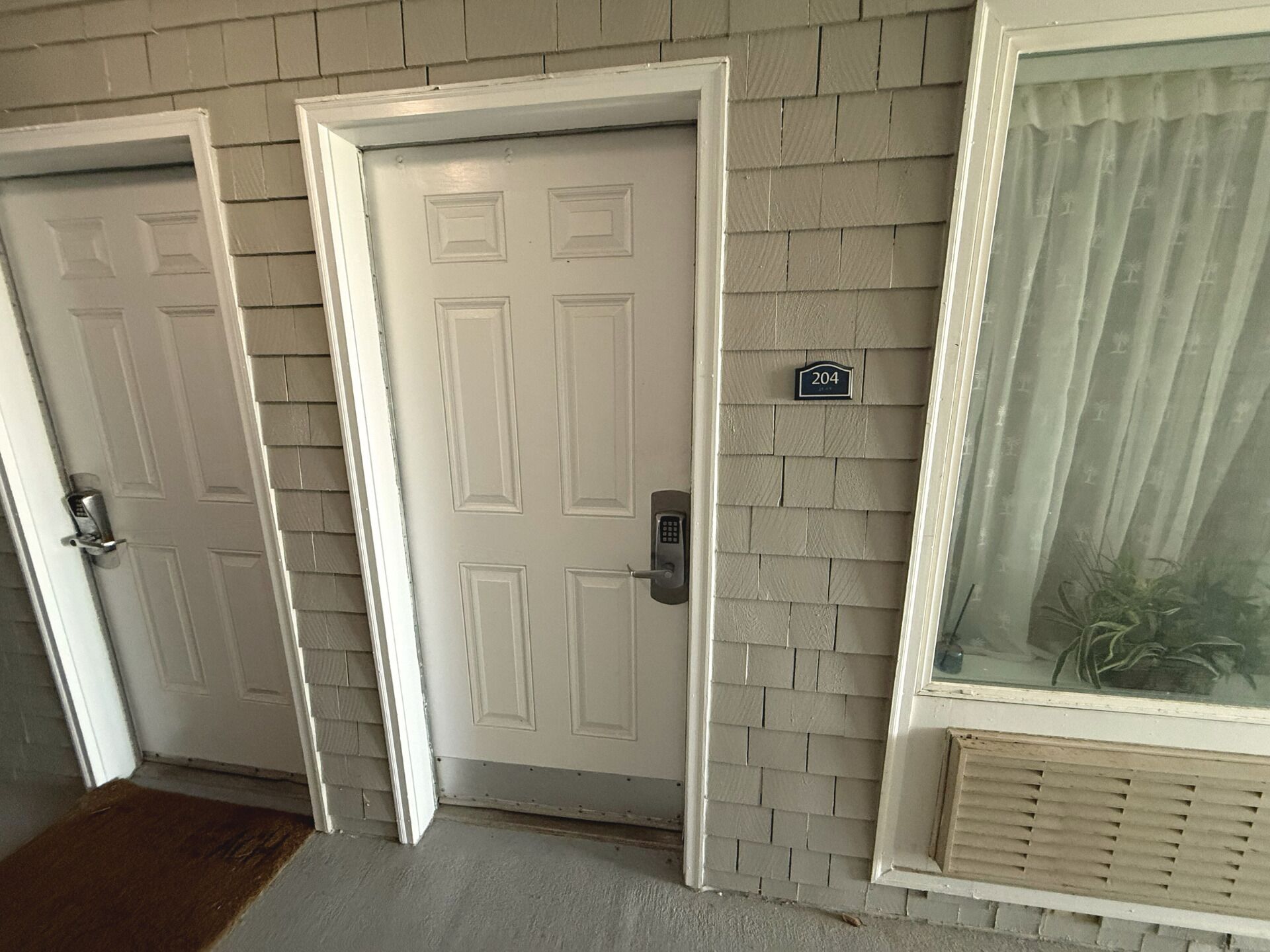 A hallway with three white doors, each with a keypad lock. A small sign with the number 204 is visible on the wall.