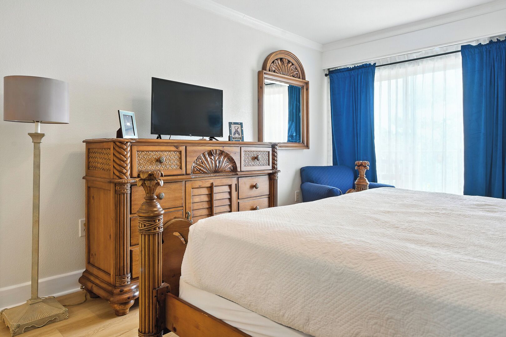 Una habitación de hotel con una cama grande, un aparador de madera, un televisor y una silla.