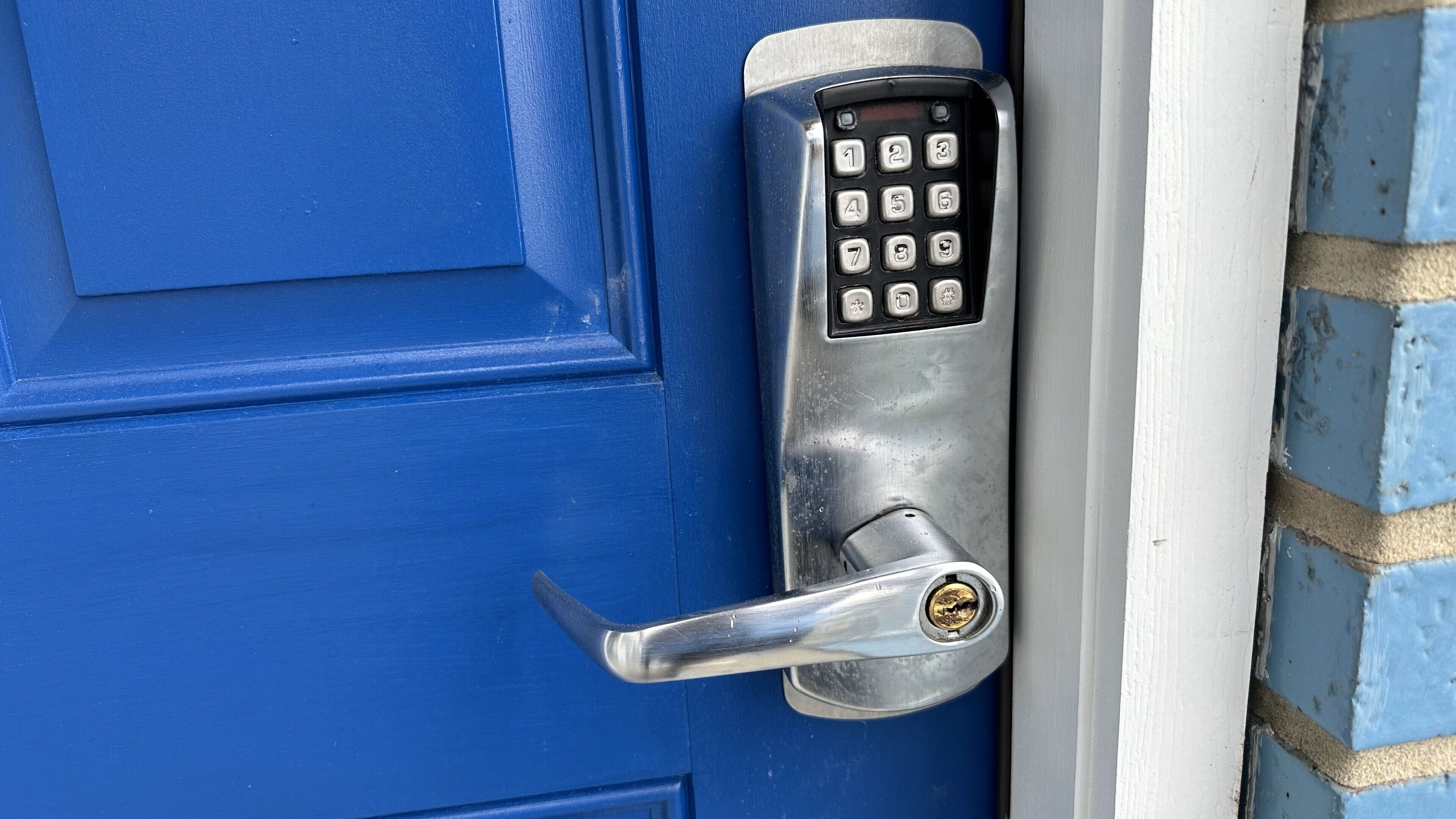Uma porta azul com teclado numérico e fechadura.