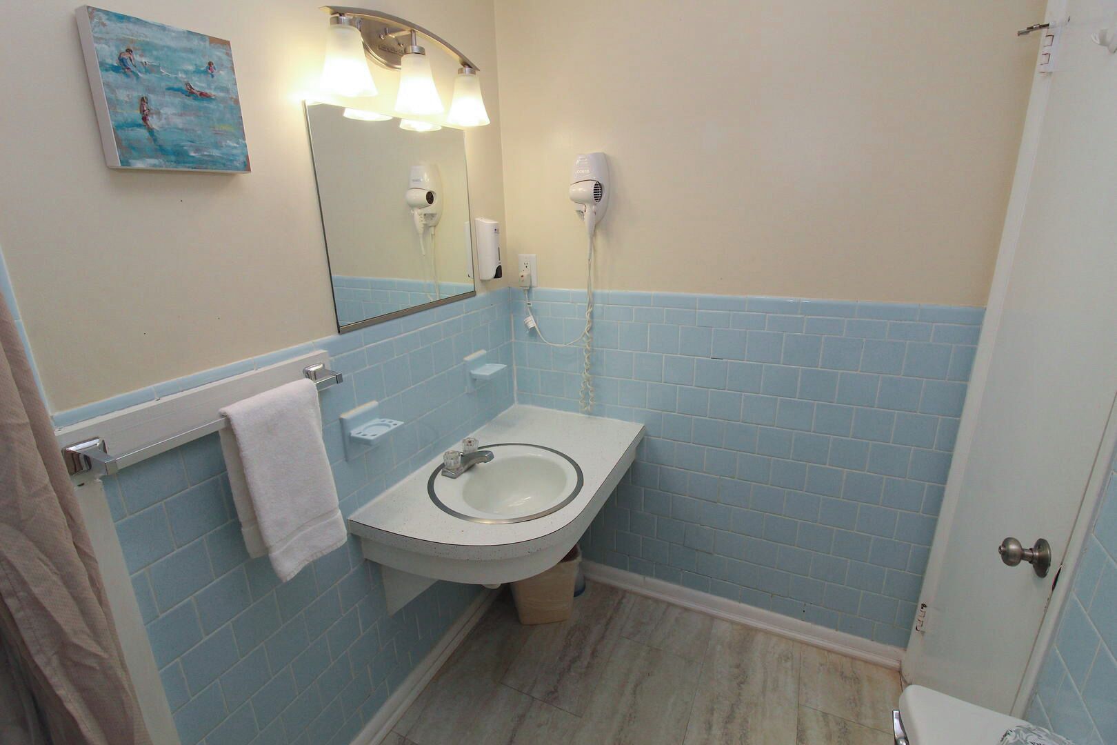 A bathroom with a sink, mirror, and two hair dryers mounted on the wall.