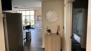A modern kitchen with a built-in refrigerator, a dining area with a table and chairs, and a large wall clock.