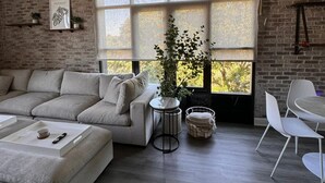 A modern living room with a sectional sofa, a round coffee table, and a dining area with white chairs.