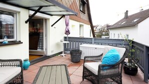 A balcony with wicker furniture, a small table, and a potted plant. - 2-room apartment in prime city center location with terrace & DreiWelten-Card (Bad Dürrheim)