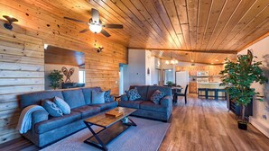 A spacious living area with a wooden ceiling, a large sofa, a coffee table, and a dining area with bar stools. - Anni's Cottage, Free Wi-Fi and Air Conditioning (Indian River)