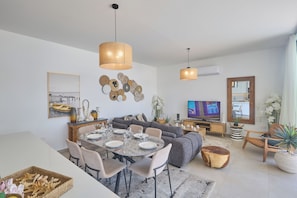 A modern living room with a dining area, a sofa set, a TV, and decorative wall art.