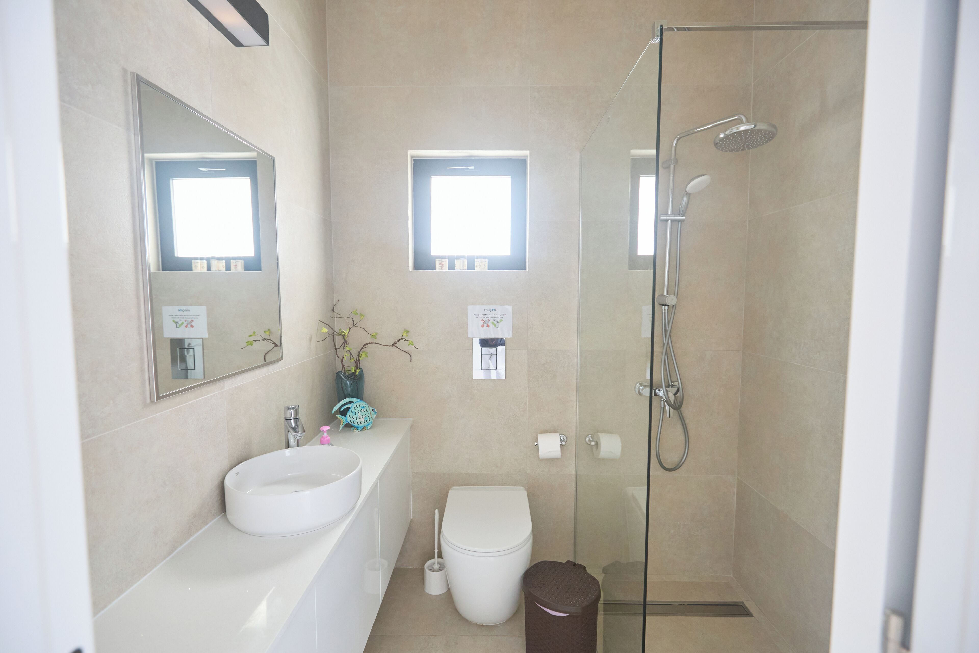 Un baño moderno con ducha de vidrio, lavamanos blanco y retrete.