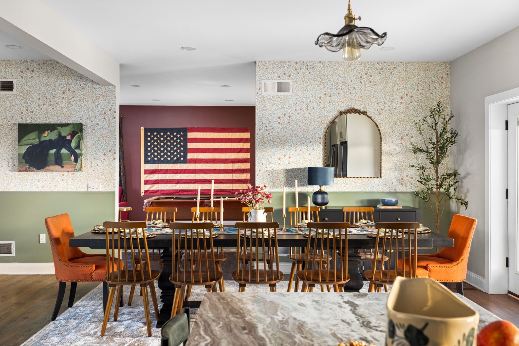 A dining area with a table set for six, surrounded by wooden chairs. An American flag is displayed on the wall behind the table.