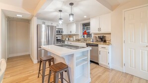 A modern kitchen with white cabinetry, stainless steel appliances, and a central island with stools. - Modern 3-bedroom Escape in Northwest Reno (Reno)