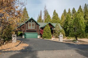 A cabin with a green roof, a garage, and stone pillars. - Handels Pride- Family friendly, Game Room & Views (Shaver Lake)