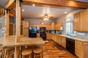 A kitchen with wooden cabinets, granite countertops, a black refrigerator, a microwave, and a dishwasher. - Handels Pride- Family friendly, Game Room & Views (Shaver Lake)
