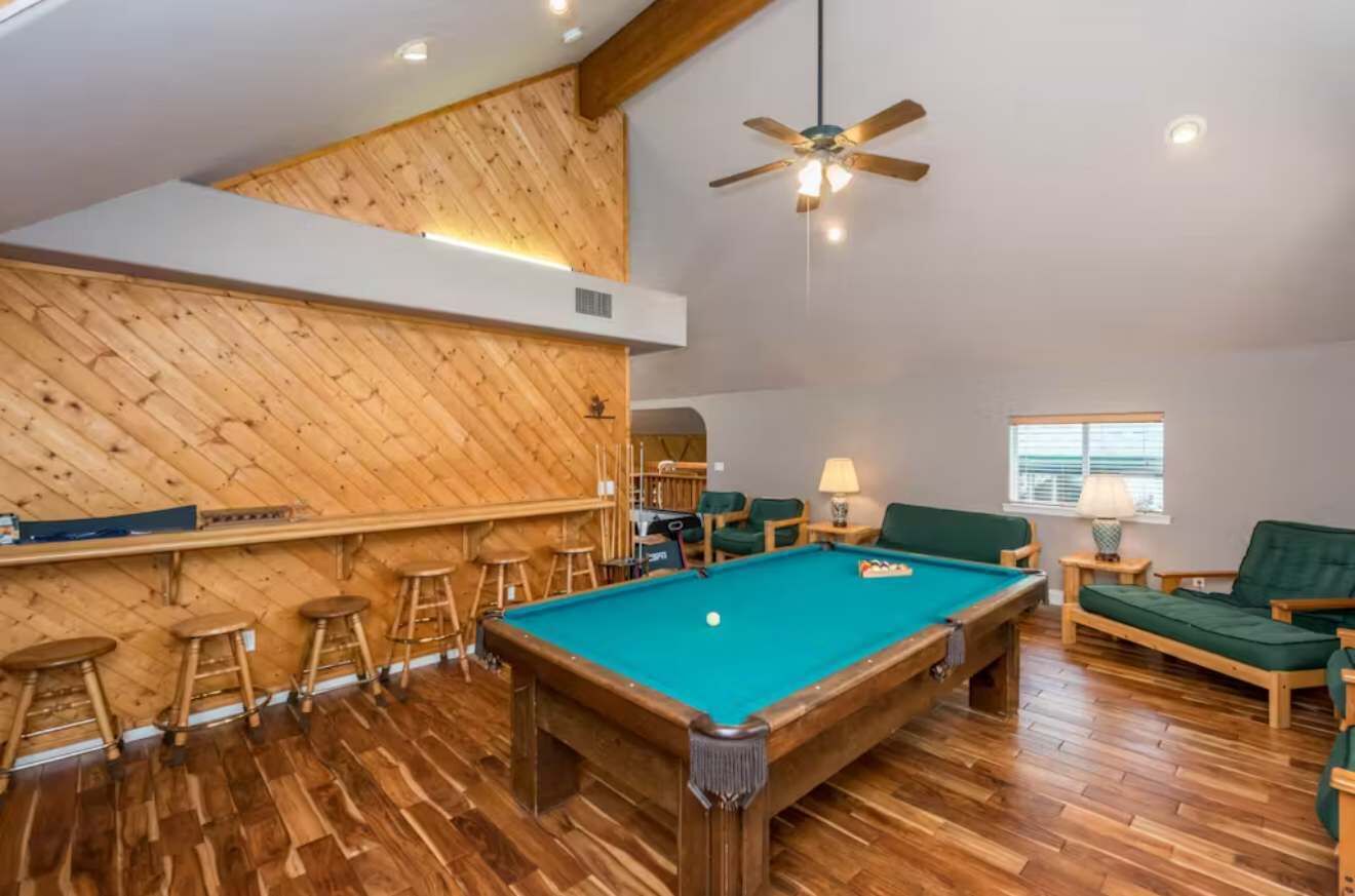 A pool table in a room with wooden flooring and a sloped ceiling.