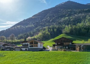 Un pueblo rural con casas tradicionales, cielo despejado y una montaña al fondo.