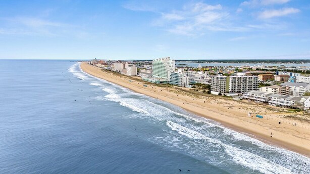 A coastal cityscape with a beach, buildings, and a clear sky.