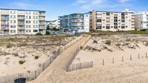 A beachfront hotel with multiple floors, balconies, and a sandy beach area.