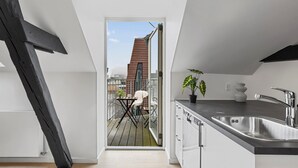 Una cocina moderna con un lavaplatos integrado y vistas a un balcón con mesa y sillas.