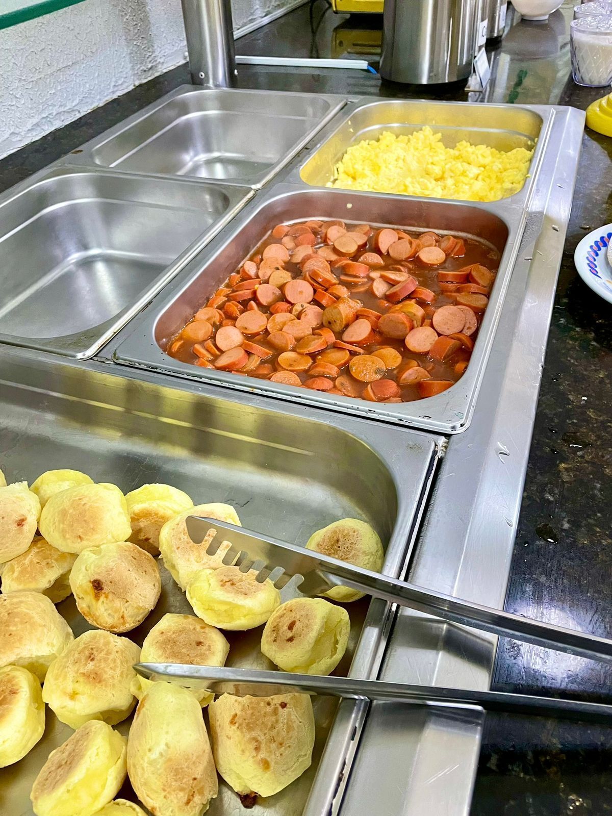 Ein Buffet mit verschiedenen Speisen, darunter Wurstscheiben, Rührei und Bratkartoffeln.