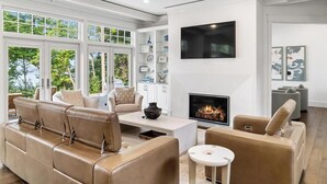 Un salon moderne avec une cheminée, des canapés en cuir et une grande fenêtre.