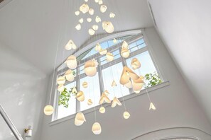 A room with a large window and multiple hanging light fixtures. - Blue Beech Estate- Beautiful Waterfront Estate! (Harbor Springs)