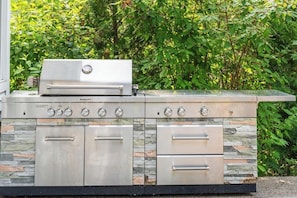 A stainless steel outdoor kitchen with a built-in grill, multiple cooking burners, and storage drawers.