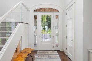 A modern interior with a glass railing, a wooden bench, and a patterned rug. - Blue Beech Estate- Beautiful Waterfront Estate! (Harbor Springs)