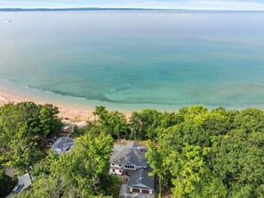 A residential area with a beachfront view, including houses and dense trees.