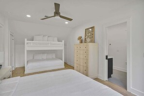 Quarto com cama beliche, penteadeira e ventoinha no teto.