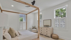 A bedroom with a four-poster bed, a dresser, a chair, and a window with shutters. - Newly Remodeled | Watercolor Resort | Golf Cart! (Santa Rosa Beach)
