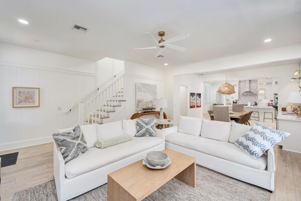 A modern living room with a white sofa, a wooden coffee table, and a staircase leading to another level.