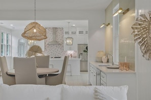 Una cocina moderna con armarios blancos, una isla central e iluminación colgante.