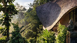 A traditional building with a curved roof, surrounded by lush greenery and a statue. - Belalu Bali Boutique & Spa Experience (Ubud)