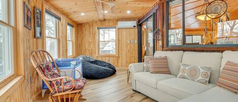 Un interior de madera acogedor con una mecedora, un sillón de peluche y un sofá.