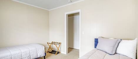 A bedroom with two single beds, a ceiling fan, and a door leading to another room.