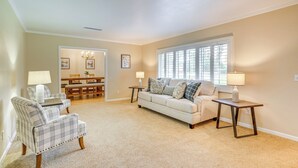 A living room with a sofa, two armchairs, a coffee table, and a dining area in the background.