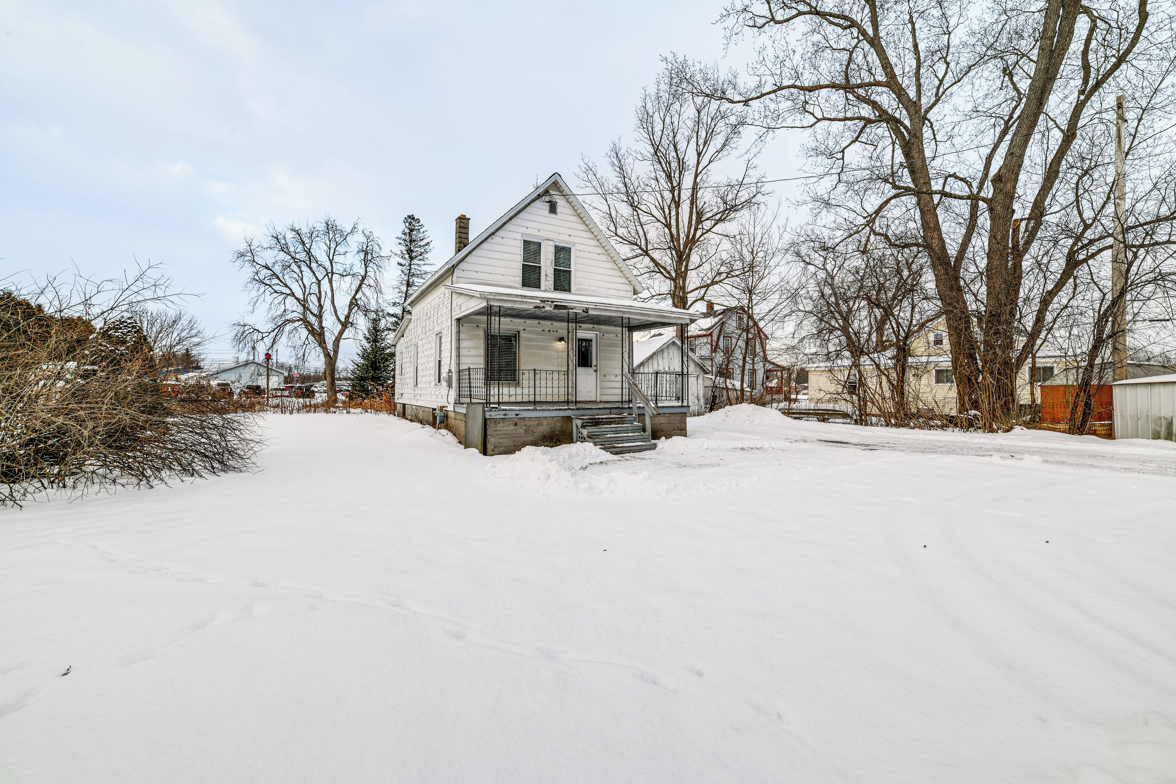 Ein mit Schnee bedecktes Wohnhaus mit Wintervorbau und Treppe zum Eingang.