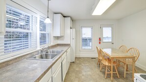 Una cocina moderna con un ventanal grande, lavavajillas integrado y un comedor con sillas de madera.