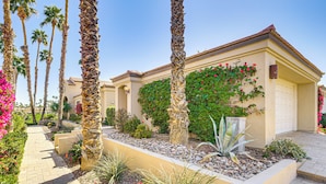 A residential building with a paved walkway, palm trees, and a variety of plants. - Community Pools & Golf Views: Palm Desert Condo! (Palm Desert)