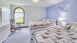 Een slaapkamer met een bed, een schommelstoel, een kast en een raam met uitzicht.