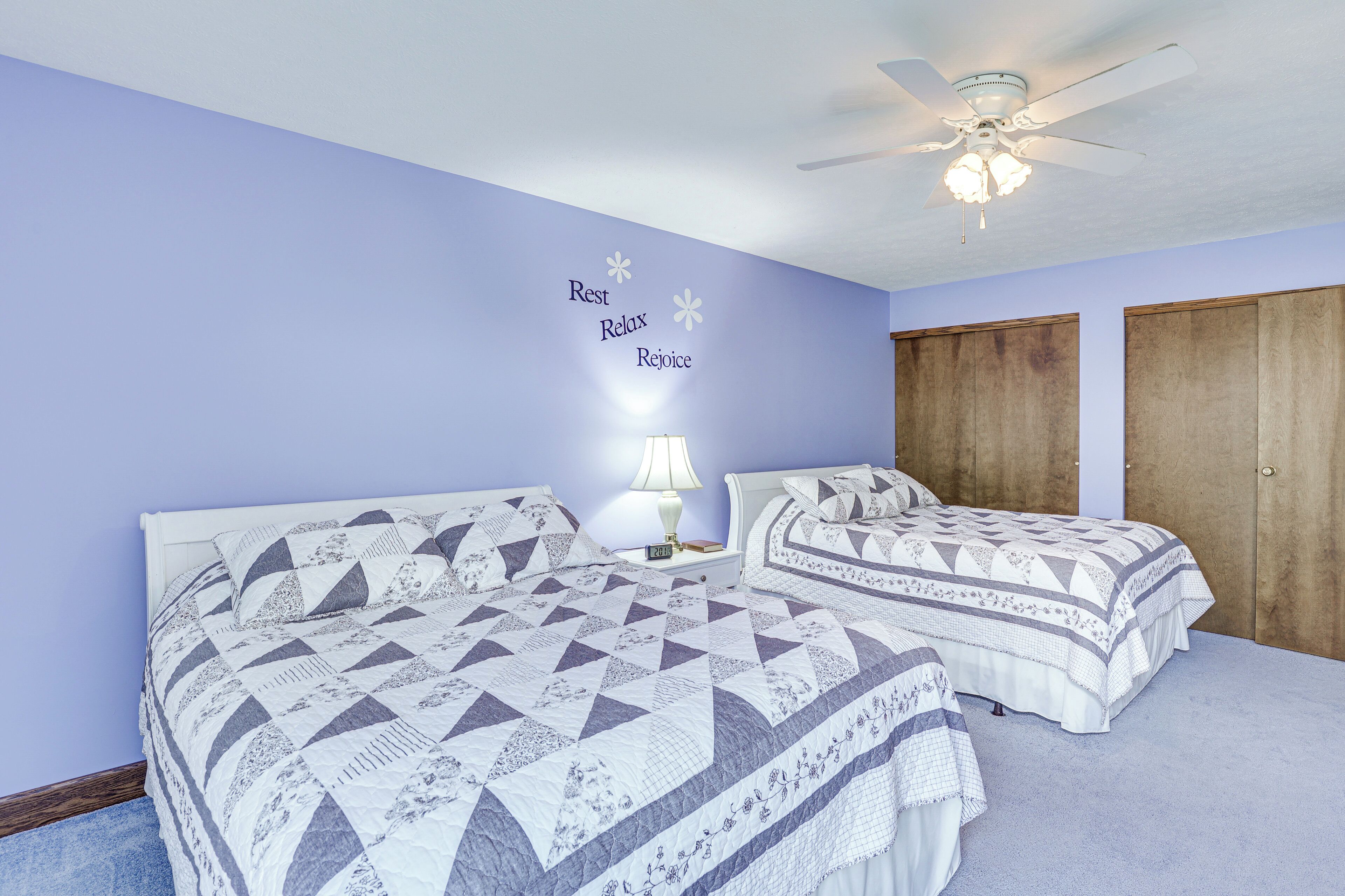 Ein Schlafzimmer mit zwei Betten, einem Deckenventilator und einer Wand mit motivierenden Texten.